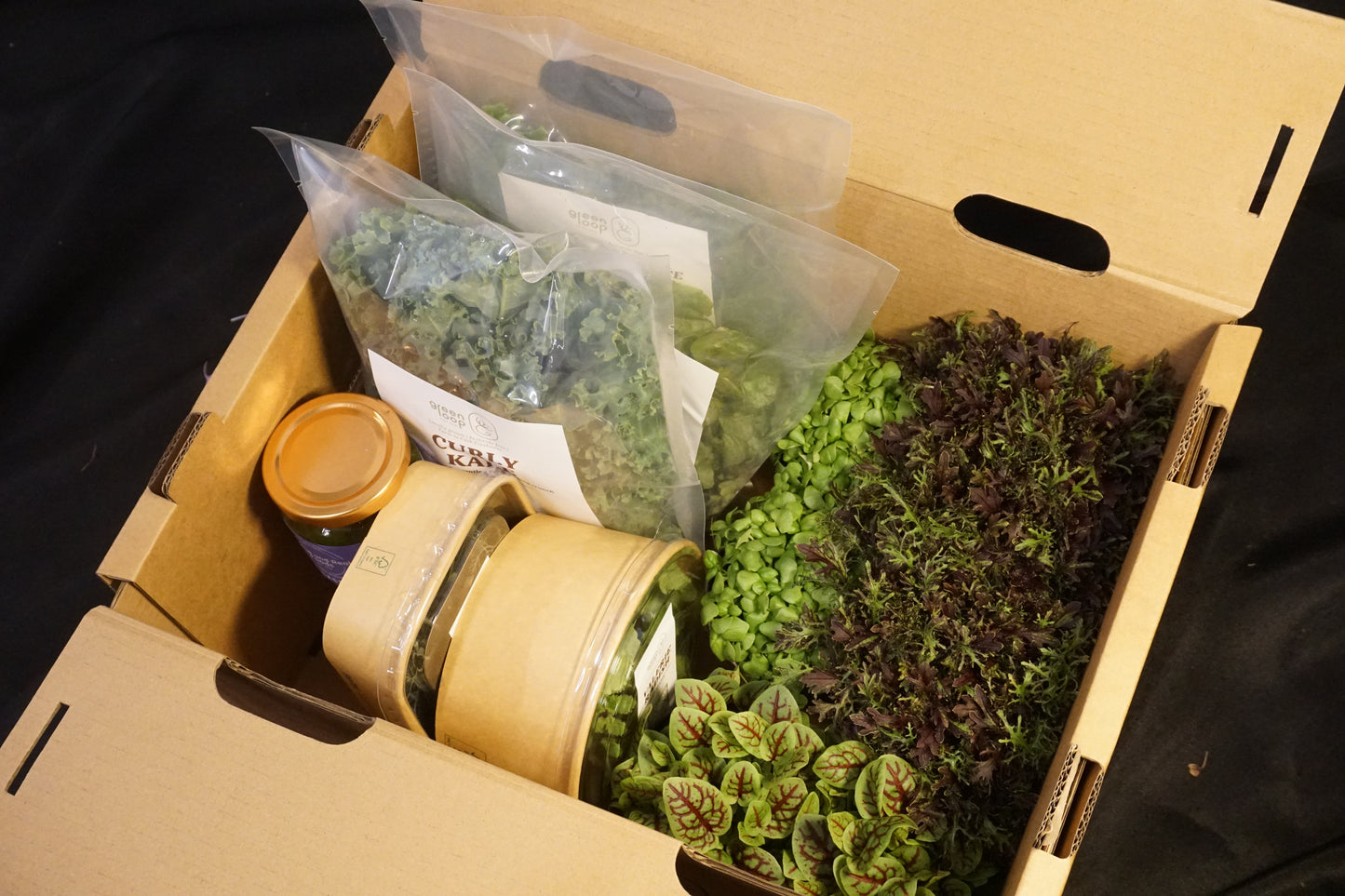 Box of packaged leafy greens, herbs, and microgreen pots