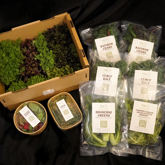 Assorted packaged leafy greens, herbs, and a box of microgreens pots